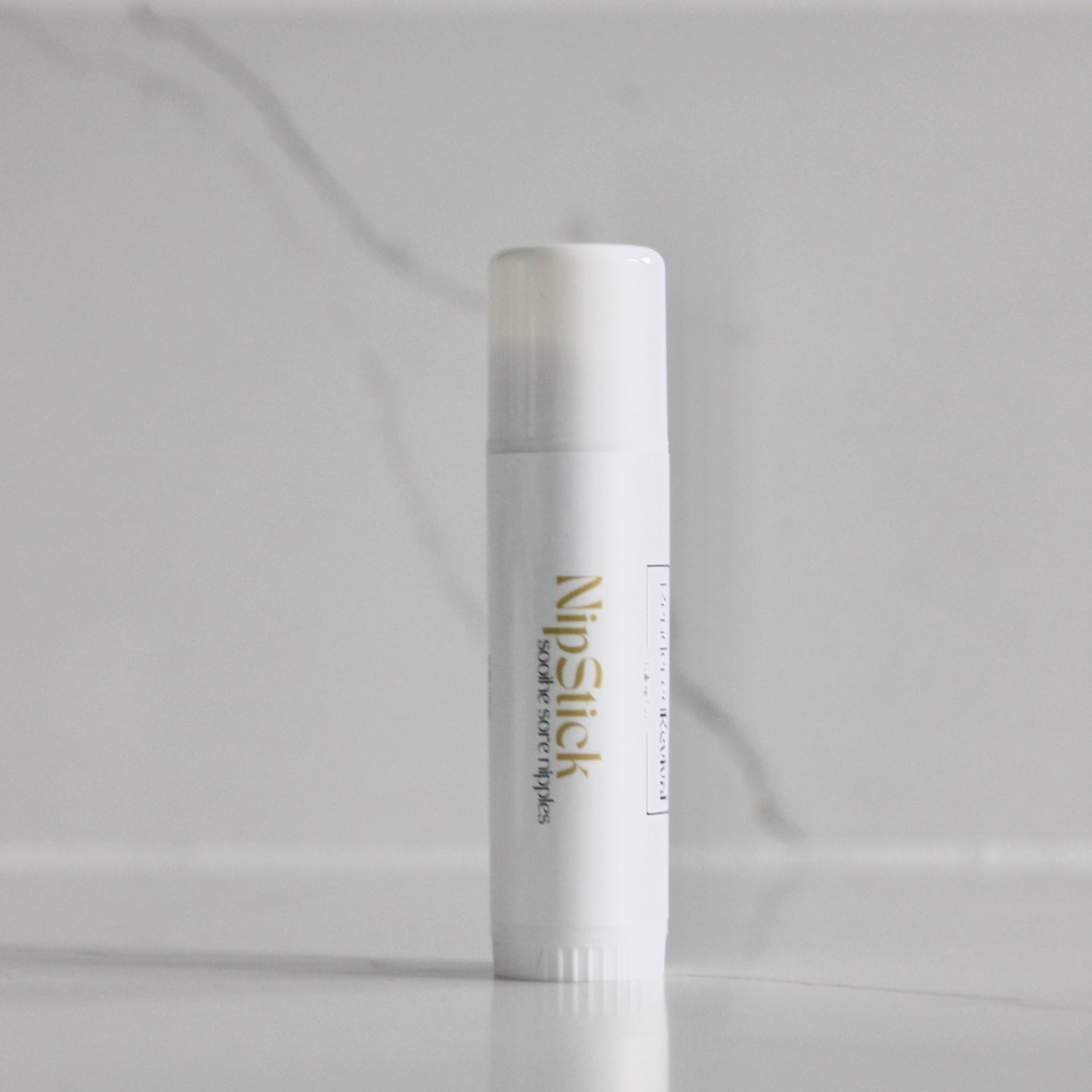 0.5 oz nip stick, a skincare essential, presented in a sleek white tube adorned with a white label and vibrant yellow font, standing upright with elegance and simplicity against a clean background